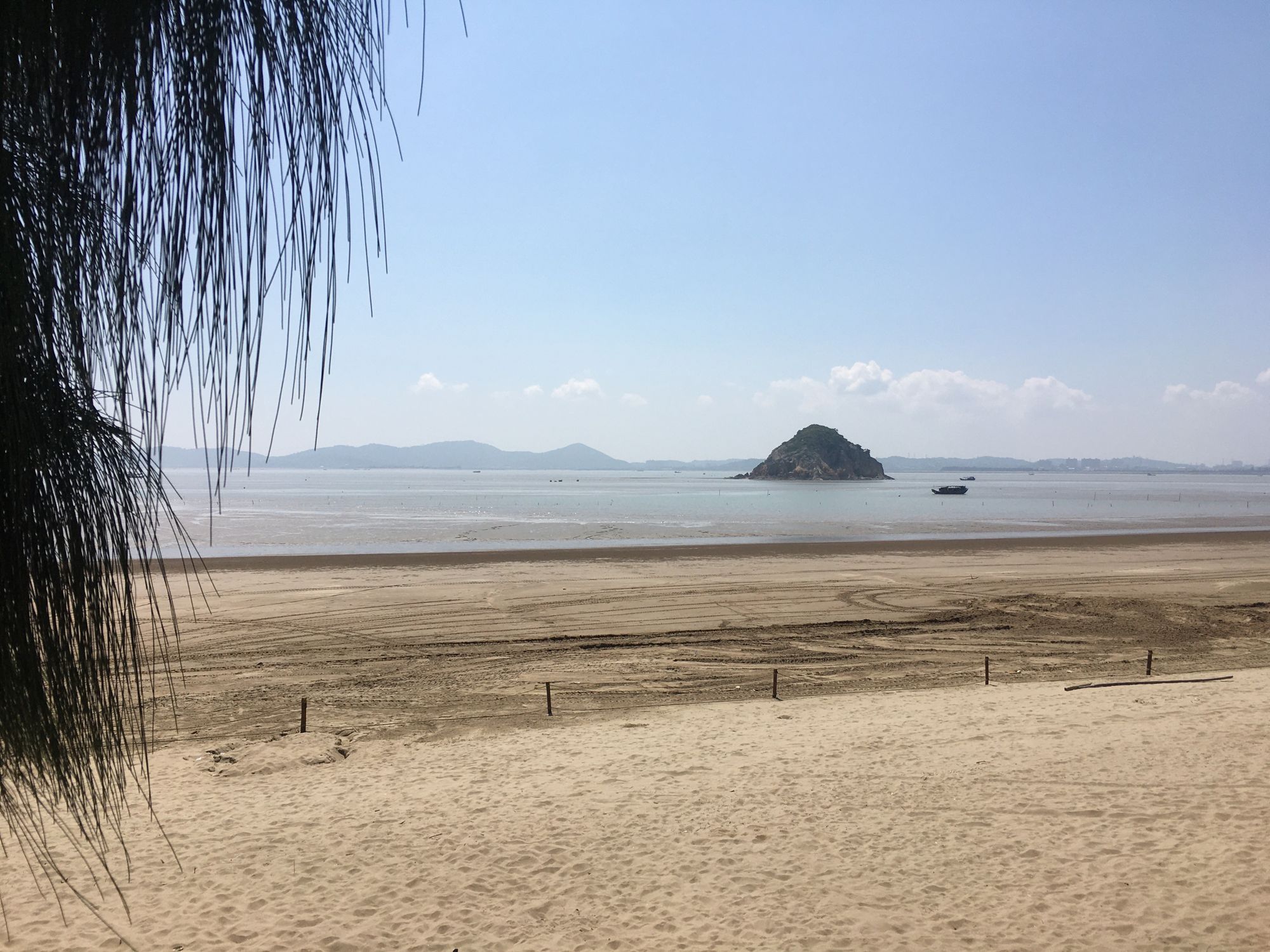 度假村门口的沙滩，远处海上有一座小礁石